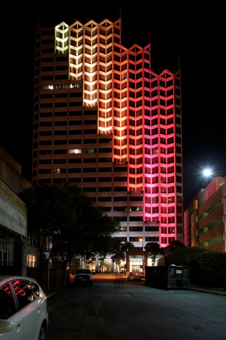A large building with white, orange, and red lights outside.
